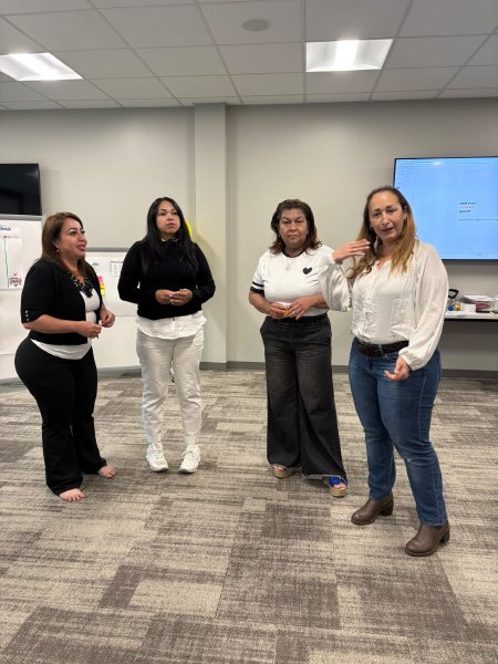 Cuatro participantes de pie practican una presentación.