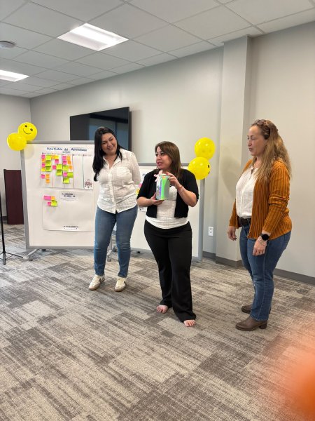 Tres participantes presentan frente a un rotafolio lleno de notas adhesivas.