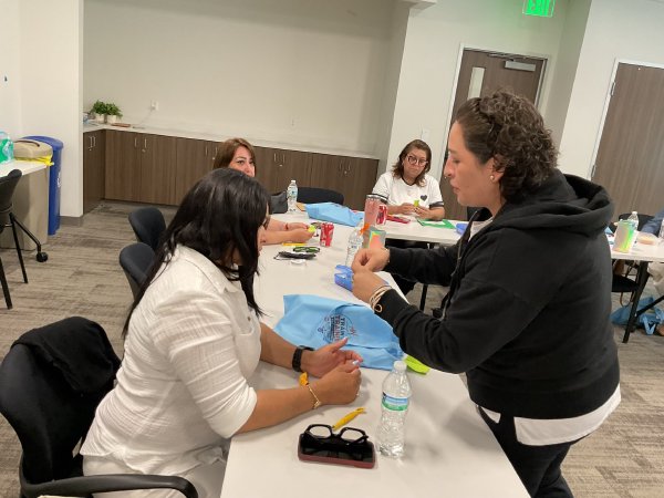 Participantes trabajan en equipo en una mesa con materiales.