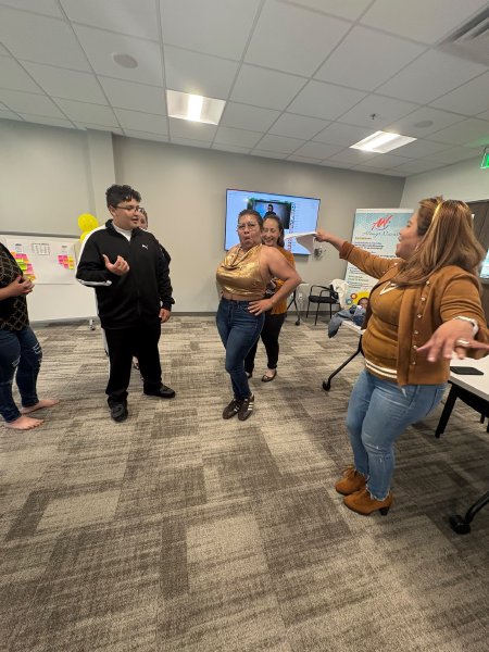 Participantes practican una dinámica de pie en el centro del salón.
