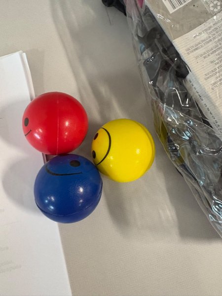 Pelotas antiestrés de colores con carita feliz sobre la mesa.