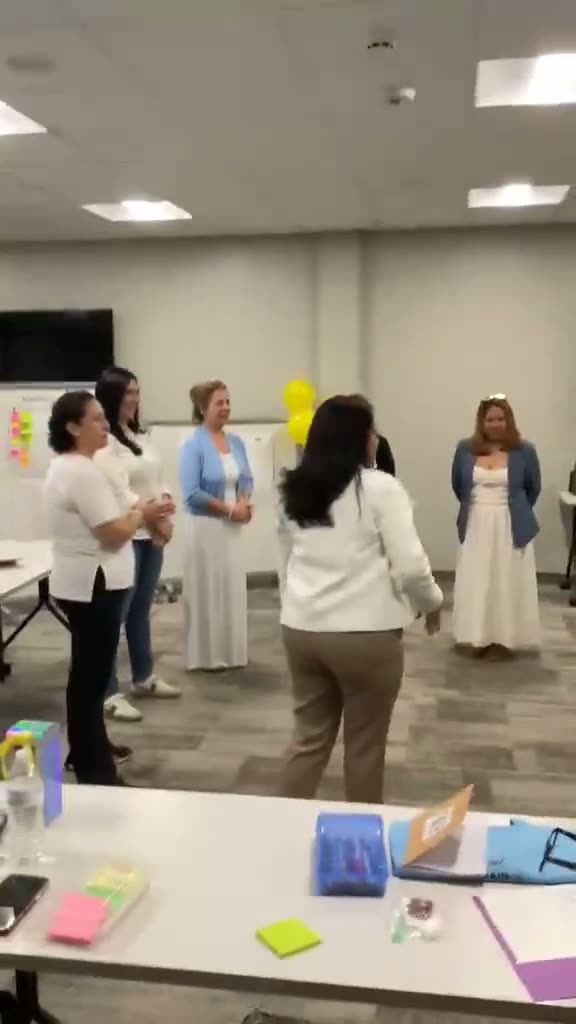 Video: Participantes de pie al fondo del salón durante una actividad en grupo.