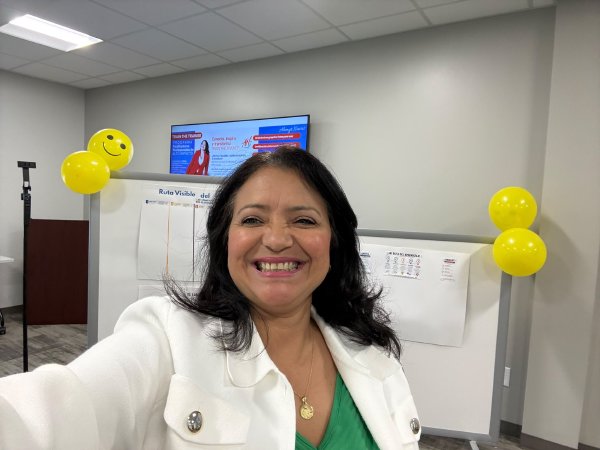 Alemyr Navas sonríe en una selfie dentro del salón del taller, con globos de carita feliz al fondo.