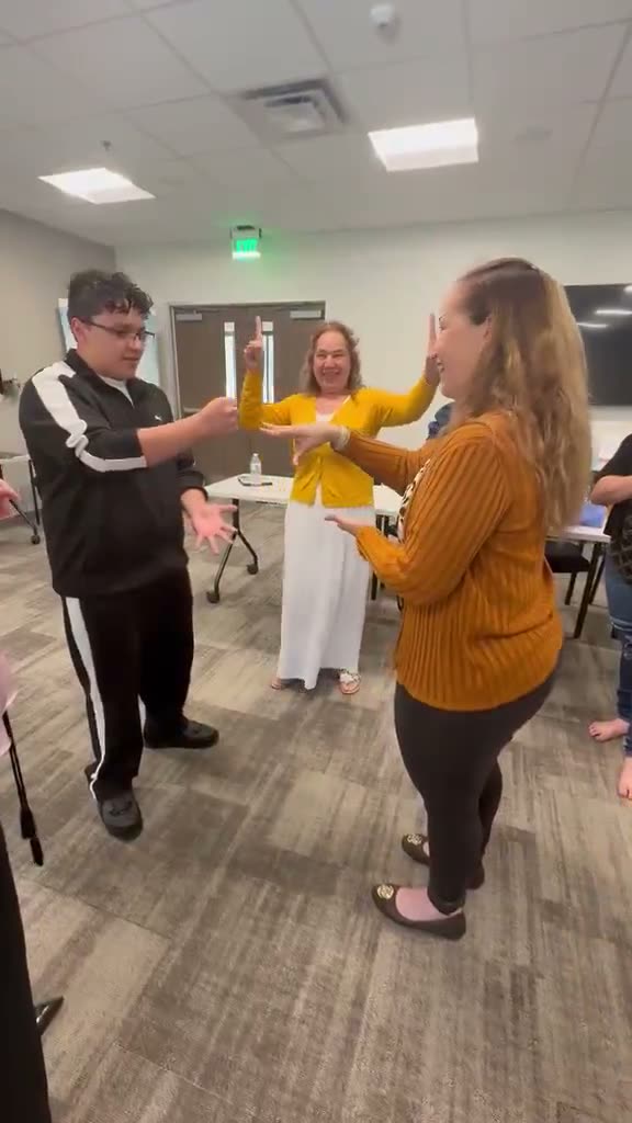 Video: Participantes practican una dinámica de pie.