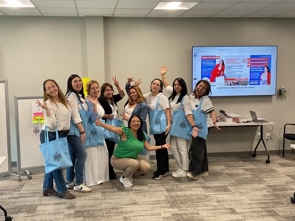 El grupo celebra con sus bolsas del taller frente a la pantalla de Train the Trainer.